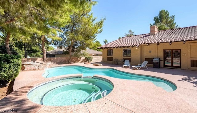 view of pool with an in ground hot tub, area for grilling, and a patio