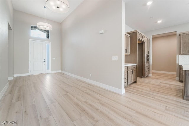 entryway featuring light wood-type flooring and high vaulted ceiling