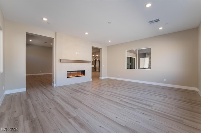 unfurnished living room featuring a large fireplace and light hardwood / wood-style floors