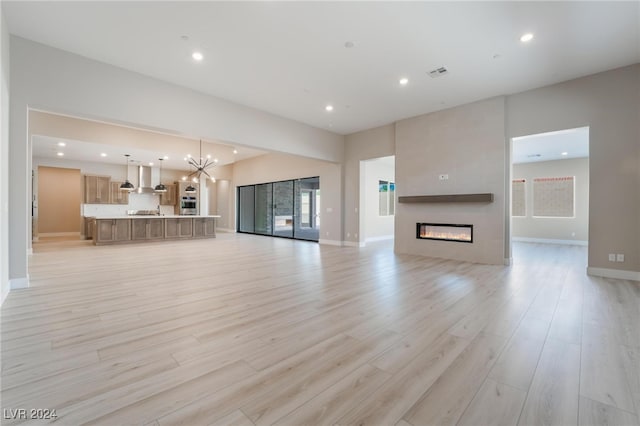 unfurnished living room with light hardwood / wood-style floors and an inviting chandelier