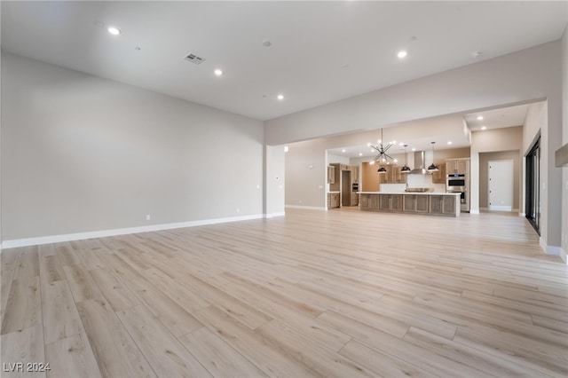 unfurnished living room with light wood-type flooring and a chandelier