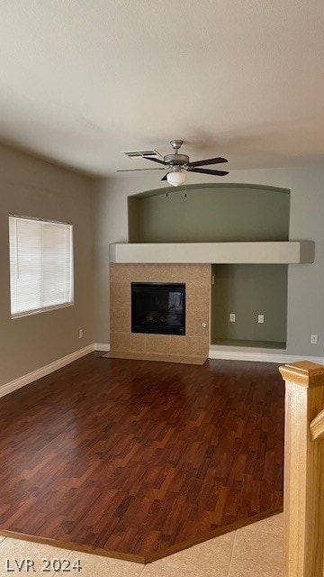 unfurnished living room featuring a fireplace, ceiling fan, and dark wood-type flooring