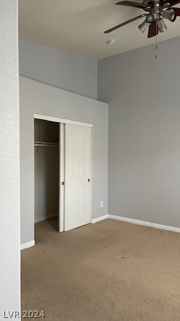 unfurnished bedroom featuring ceiling fan, a closet, and dark colored carpet