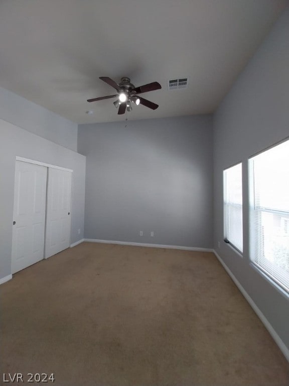 unfurnished bedroom featuring ceiling fan, a closet, and light carpet