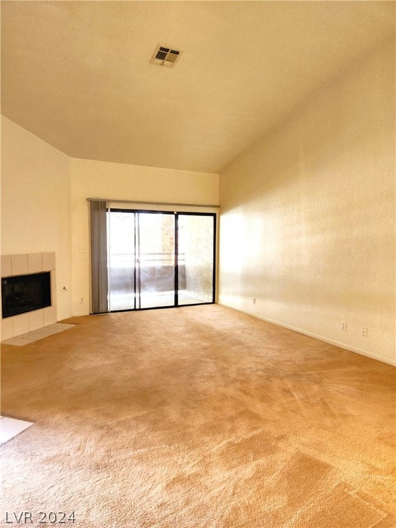 unfurnished living room featuring a tiled fireplace and light colored carpet