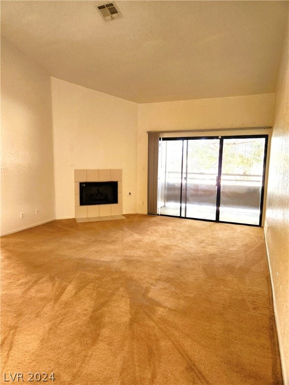 unfurnished living room with light colored carpet and a tile fireplace