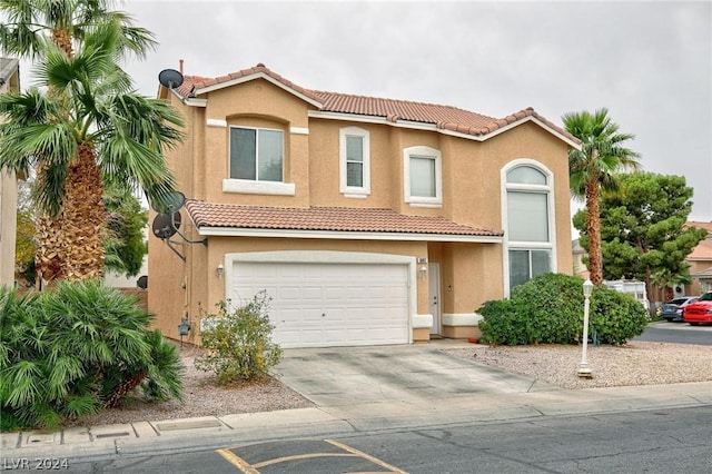 mediterranean / spanish house featuring driveway, an attached garage, a tile roof, and stucco siding