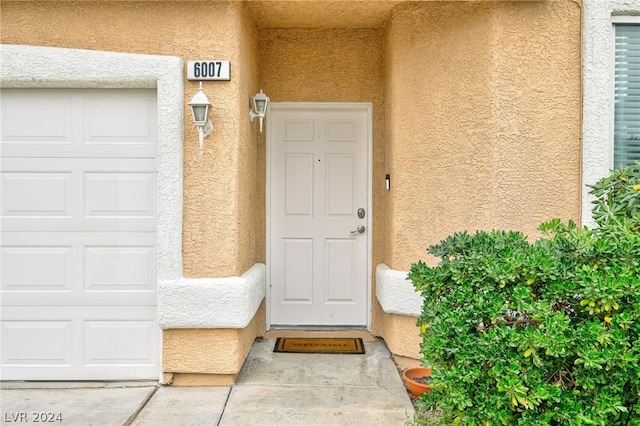 doorway to property featuring a garage and stucco siding