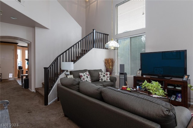 carpeted living room featuring a towering ceiling, stairs, and arched walkways