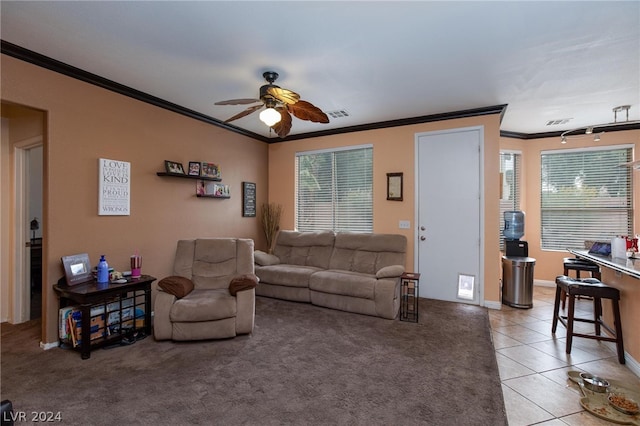 living room with light tile patterned floors, visible vents, baseboards, ceiling fan, and ornamental molding