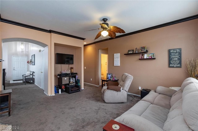 living room featuring crown molding, baseboards, carpet floors, arched walkways, and ceiling fan