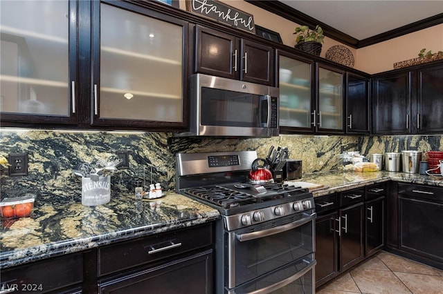 kitchen featuring light tile floors, dark stone counters, ornamental molding, appliances with stainless steel finishes, and backsplash