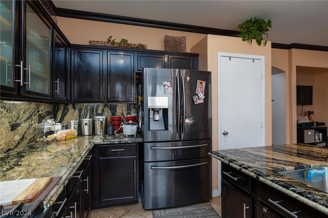 kitchen with light tile floors, dark stone counters, crown molding, backsplash, and stainless steel refrigerator with ice dispenser