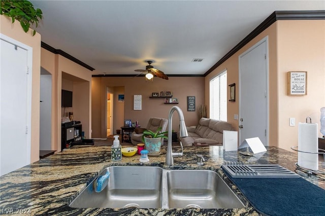kitchen featuring ornamental molding, dark stone counters, a sink, visible vents, and a ceiling fan