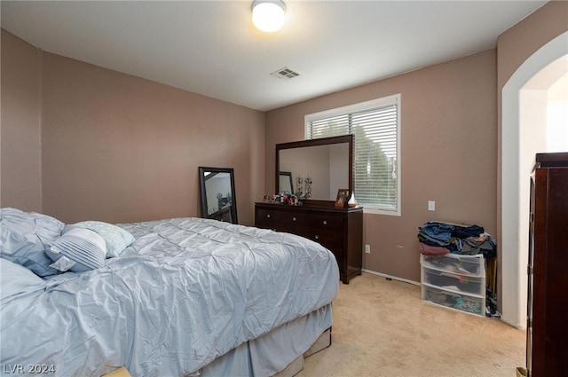 bedroom with light carpet, baseboards, visible vents, and arched walkways