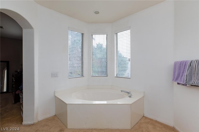 bathroom with a garden tub and baseboards