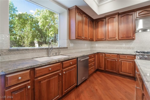 kitchen featuring hardwood / wood-style floors, sink, light stone countertops, a wealth of natural light, and appliances with stainless steel finishes