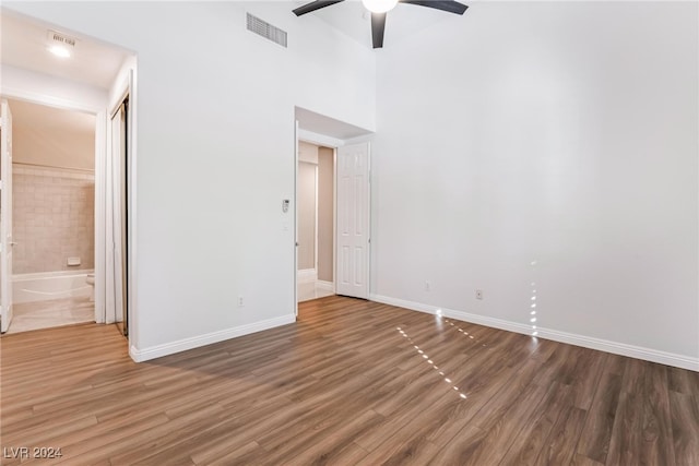 unfurnished room featuring hardwood / wood-style floors, ceiling fan, and a high ceiling