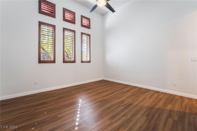 spare room featuring ceiling fan, a towering ceiling, and dark hardwood / wood-style floors