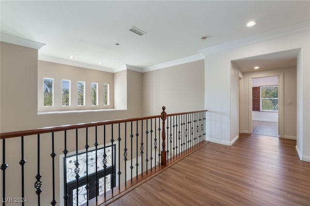 hallway with light wood-type flooring, crown molding, and a wealth of natural light