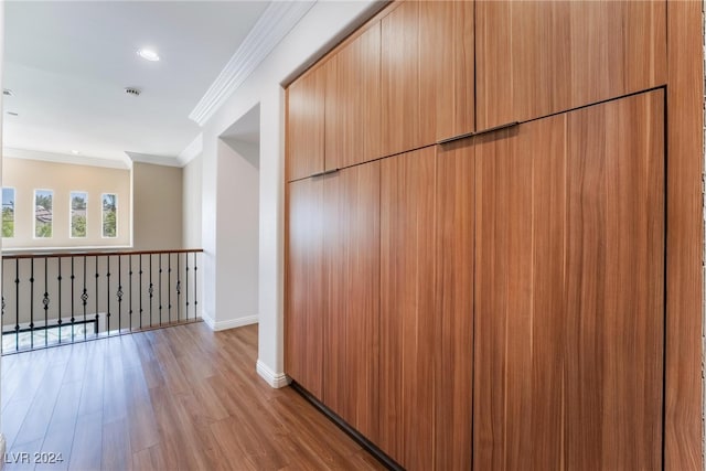 hallway featuring light wood-type flooring and ornamental molding