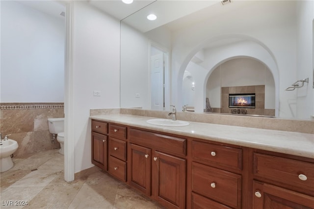 bathroom featuring tile patterned floors, vanity, a bidet, tile walls, and toilet