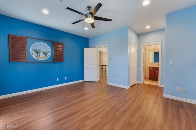 unfurnished bedroom with light wood-type flooring, ceiling fan, and connected bathroom