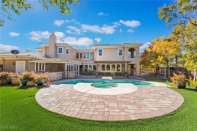 rear view of house with a swimming pool with hot tub, a patio area, and a yard