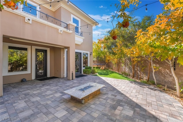 view of patio with a trampoline, a balcony, and an outdoor fire pit