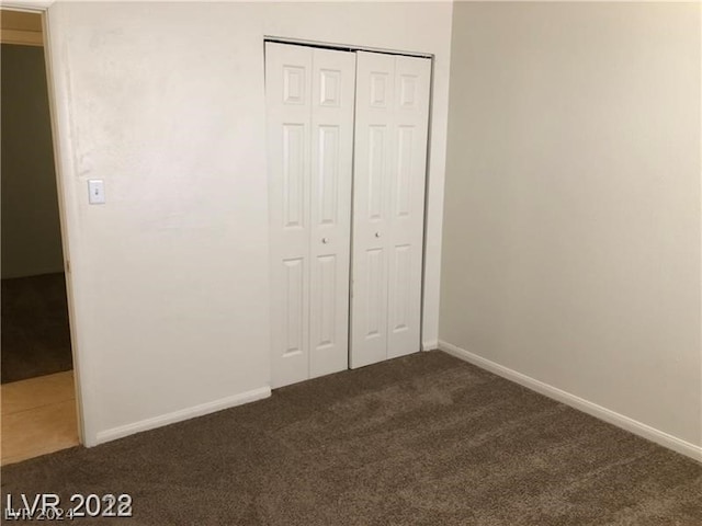 unfurnished bedroom with a closet and dark carpet