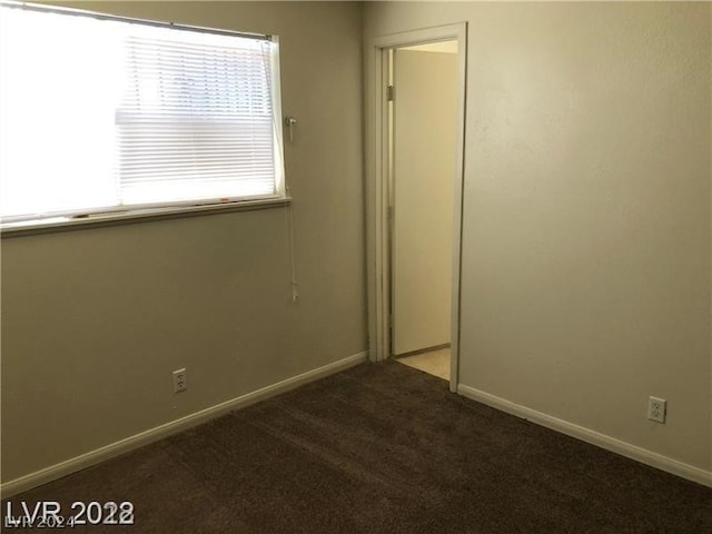 spare room featuring dark carpet