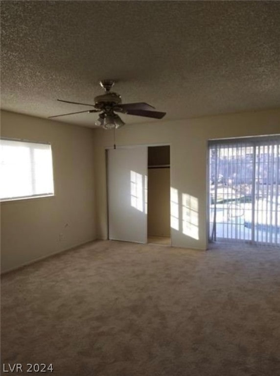 unfurnished bedroom with carpet floors, a textured ceiling, and multiple windows