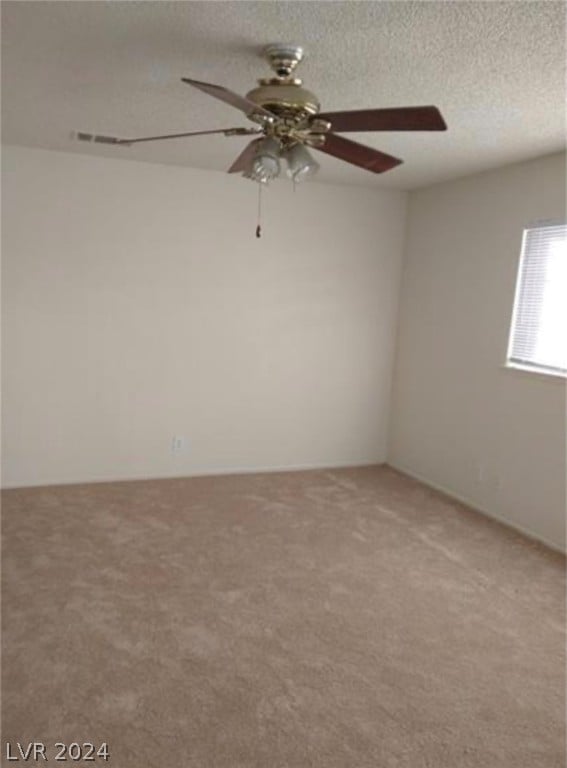 carpeted spare room with ceiling fan and a textured ceiling