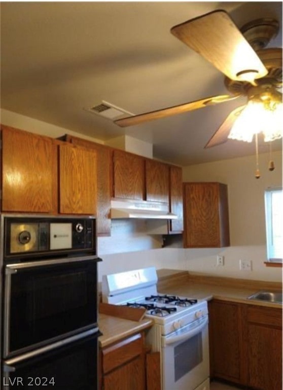 kitchen featuring white range with gas cooktop, ceiling fan, black oven, stainless steel oven, and sink