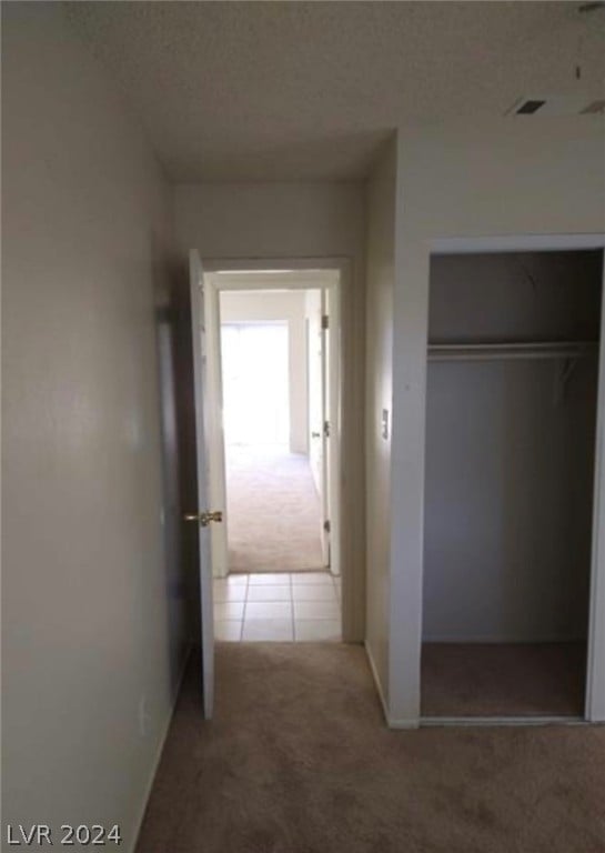 hall with a textured ceiling and light tile flooring