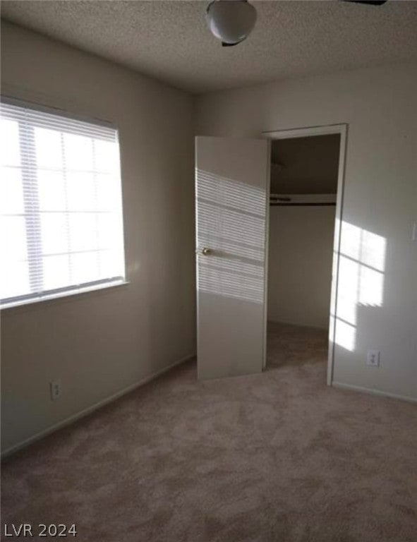 unfurnished bedroom featuring a closet, dark colored carpet, and a textured ceiling