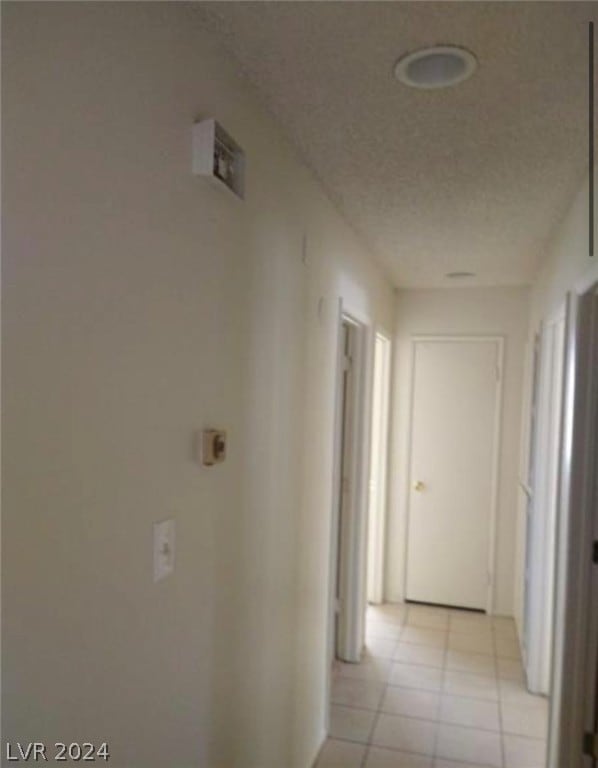 hallway featuring light tile flooring and a textured ceiling