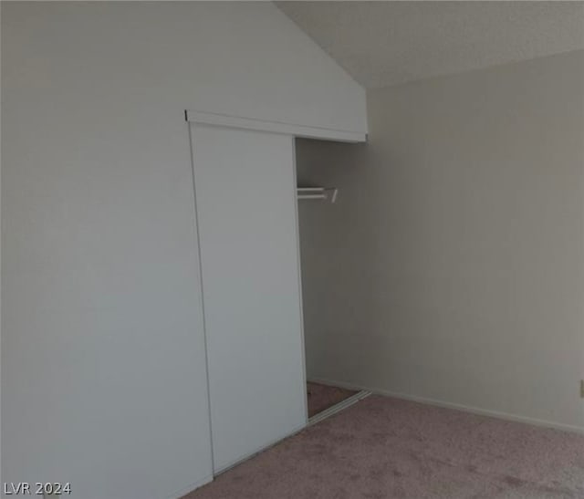 unfurnished bedroom with lofted ceiling, carpet flooring, and a closet