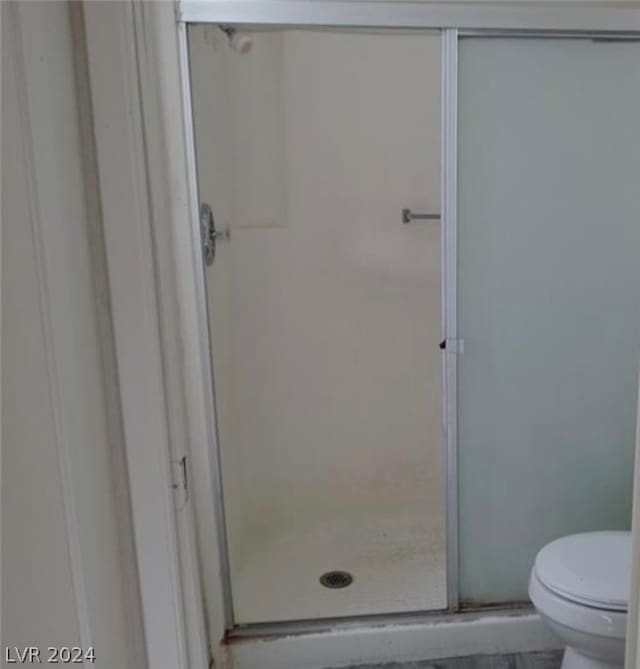 bathroom with toilet and a shower with shower door