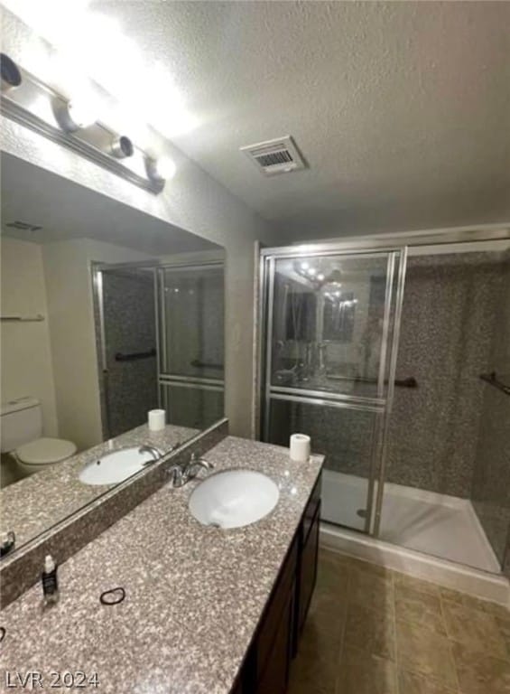 bathroom featuring toilet, an enclosed shower, tile flooring, a textured ceiling, and vanity