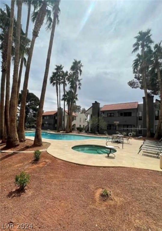 view of swimming pool featuring a patio area and a hot tub