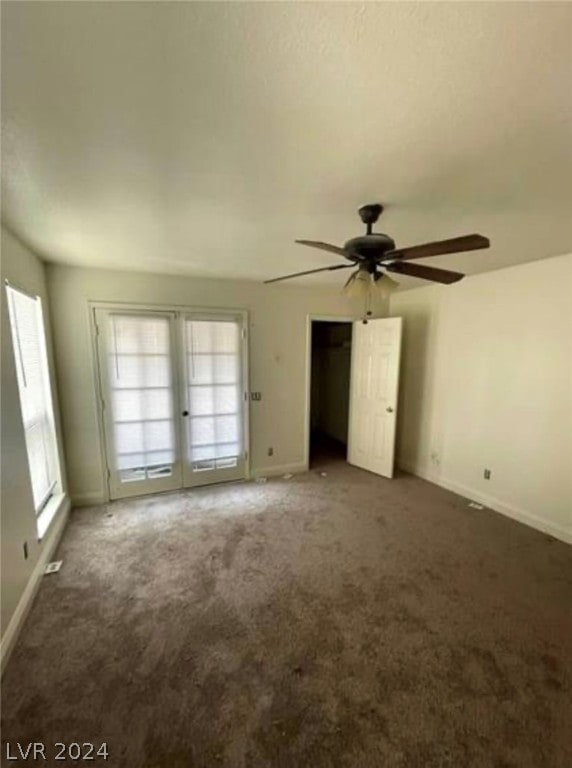 unfurnished bedroom featuring french doors, dark carpet, and ceiling fan