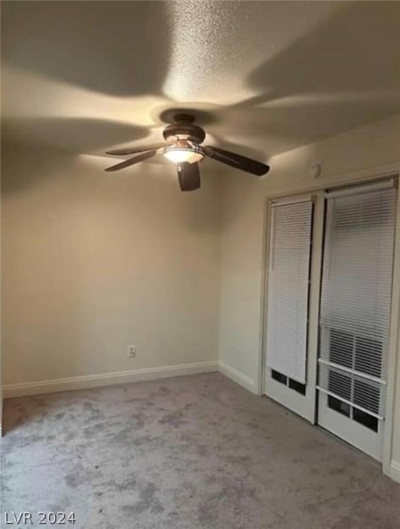 empty room with ceiling fan and dark carpet