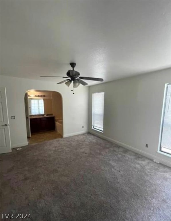 unfurnished living room with dark carpet and ceiling fan