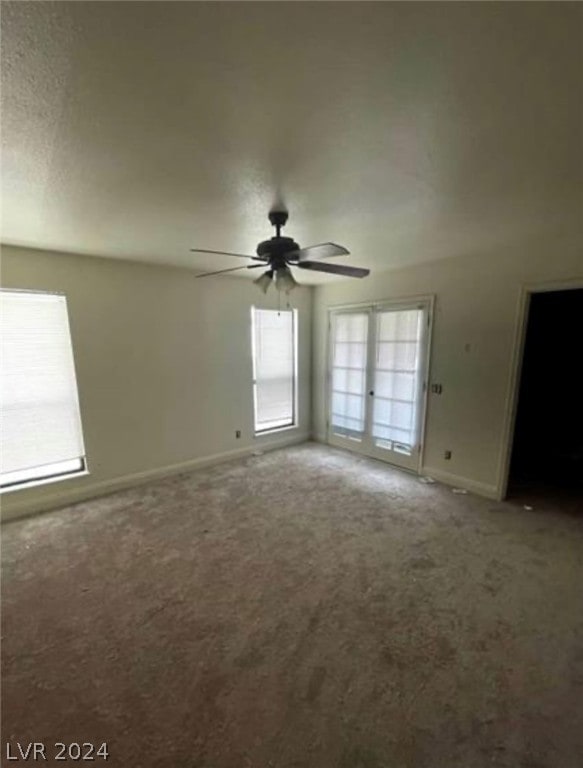 empty room featuring dark colored carpet, ceiling fan, and french doors