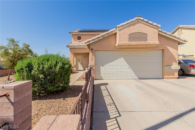 mediterranean / spanish-style home featuring stucco siding, driveway, a tiled roof, and solar panels