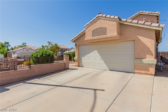 view of front of home with a garage, fence, a tiled roof, driveway, and stucco siding