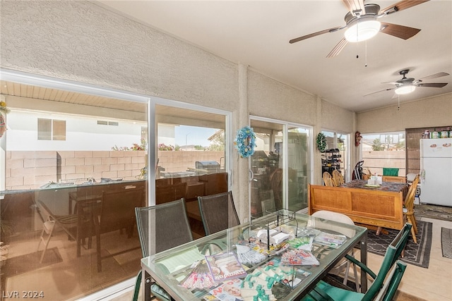 sunroom with vaulted ceiling, plenty of natural light, visible vents, and a ceiling fan