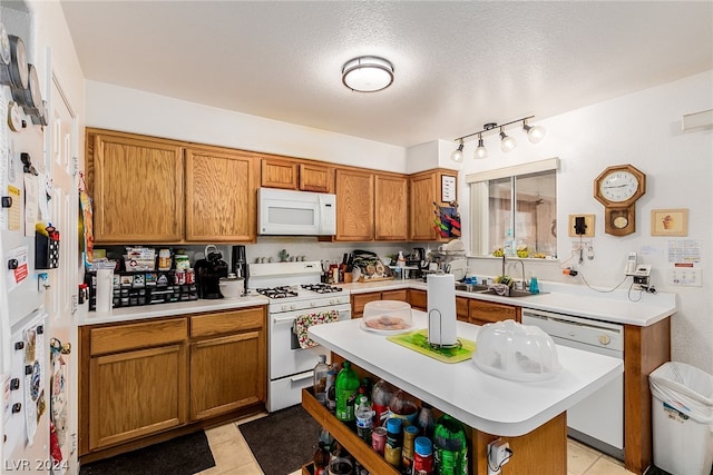 kitchen with light countertops, white appliances, a sink, and brown cabinets