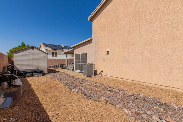 view of side of property with an outbuilding, central AC, fence, and stucco siding